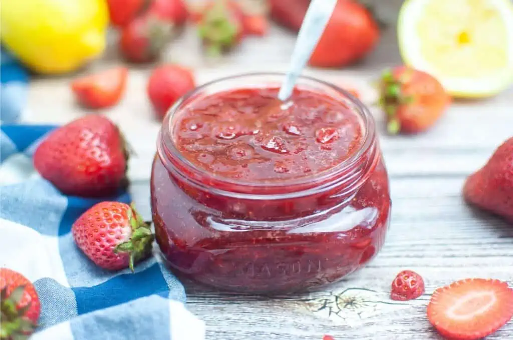 Strawberry jam recipe in a jar with strawberries.