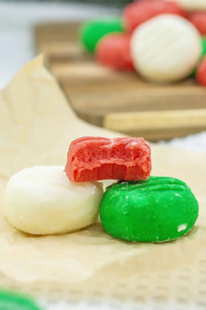 A stack of homemade red, green, and white cookies on a piece of paper.
