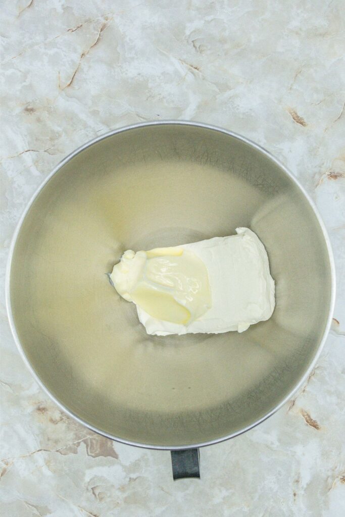 Homemade creamy peppermints placed on a marble surface next to a metal bowl filled with butter.