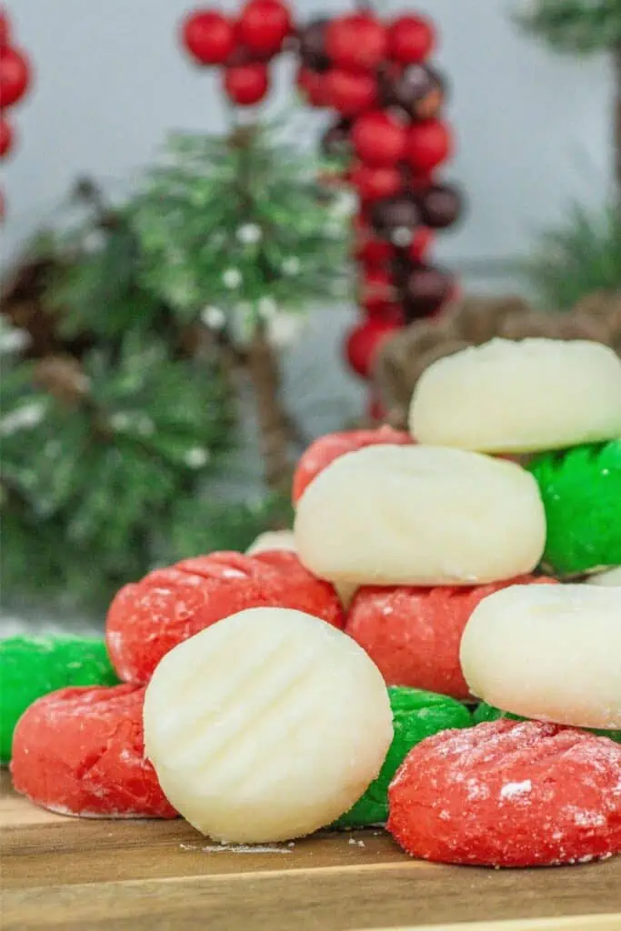 A stack of homemade Christmas cookies on a wooden cutting board.