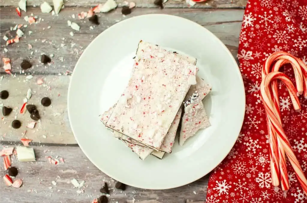 Peppermint bark on a white plate with candy canes.