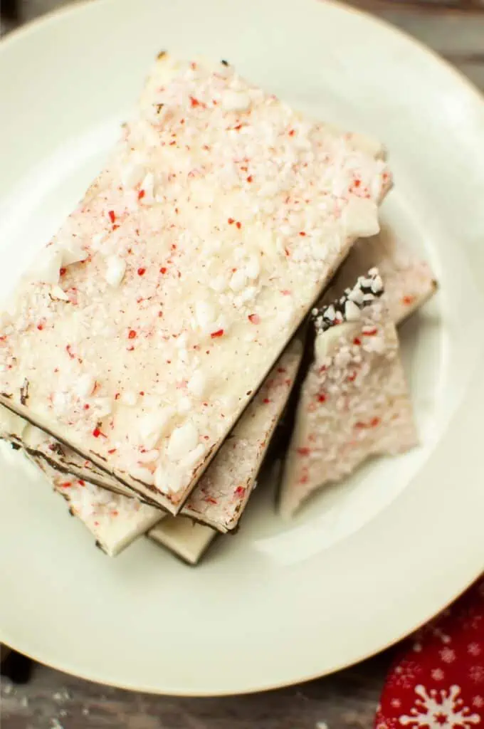 Peppermint bark on a white plate is a delicious and festive treat. The combination of rich dark chocolate and refreshing peppermint creates a delightful flavor explosion. The peppermint bark is carefully crafted with layers