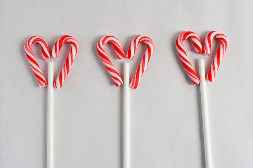 Three red and white candy canes shaped like reindeer on a stick.