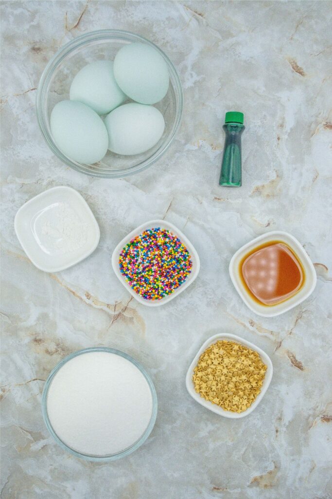 Meringue cookies adorned with sprinkles and other ingredients on a marble table.