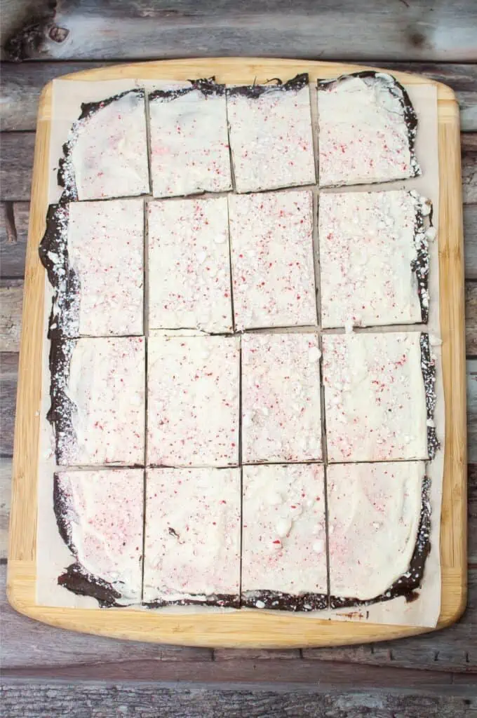 A square of peppermint bark on a wooden cutting board.