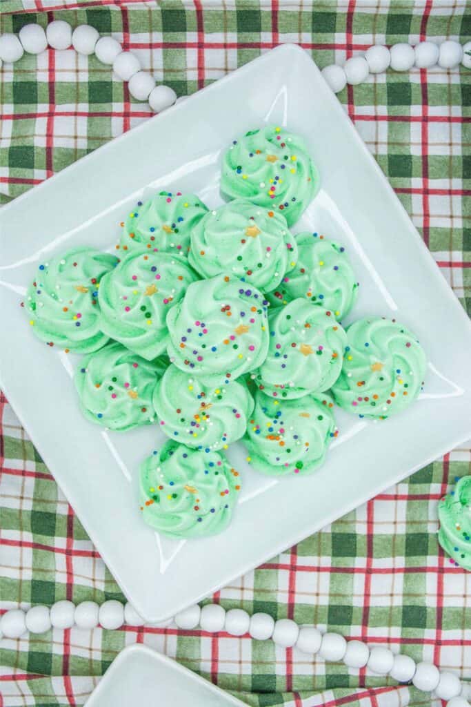 A plate of green frosted cookies with sprinkles, resembling a Christmas Tree.