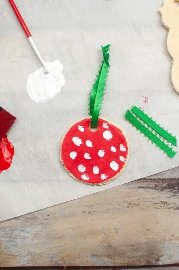 Salt dough Christmas cookie ornaments decorated with paint and paintbrushes.