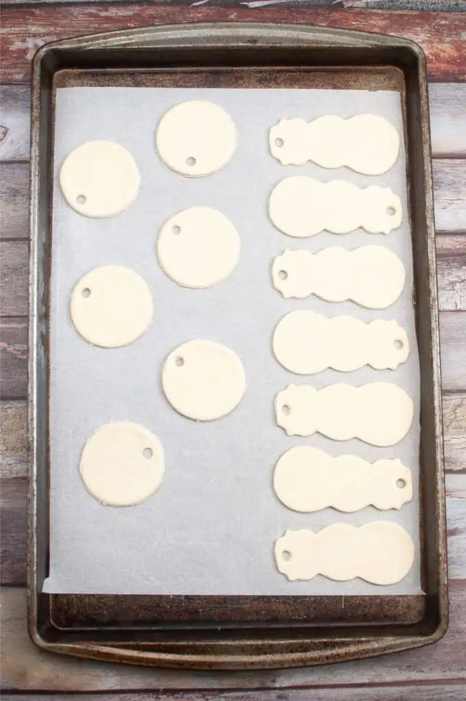 Salt dough ornaments cut with cookie cutters placed on a baking sheet.