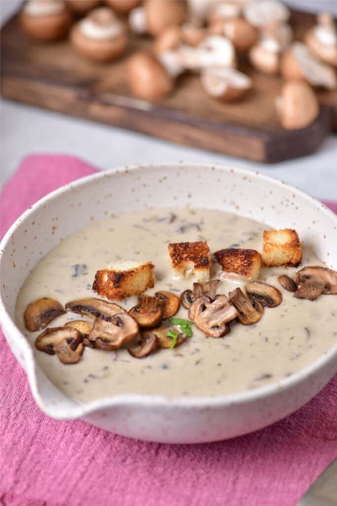 A creamy bowl of mushroom soup with croutons.
