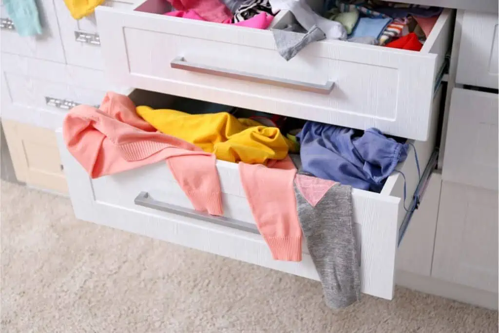 A drawer full of clothes in a white dresser, ready to be decluttered as part of organizing a house.