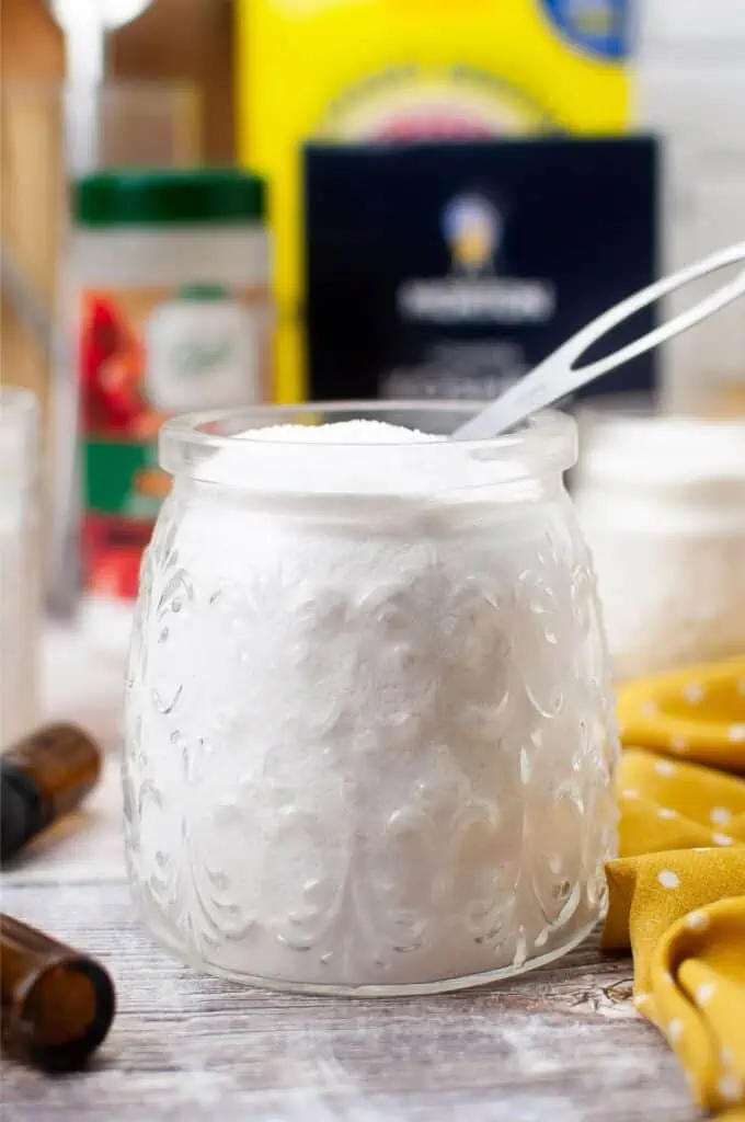 A jar of homemade dishwasher detergent with a spoon next to it.