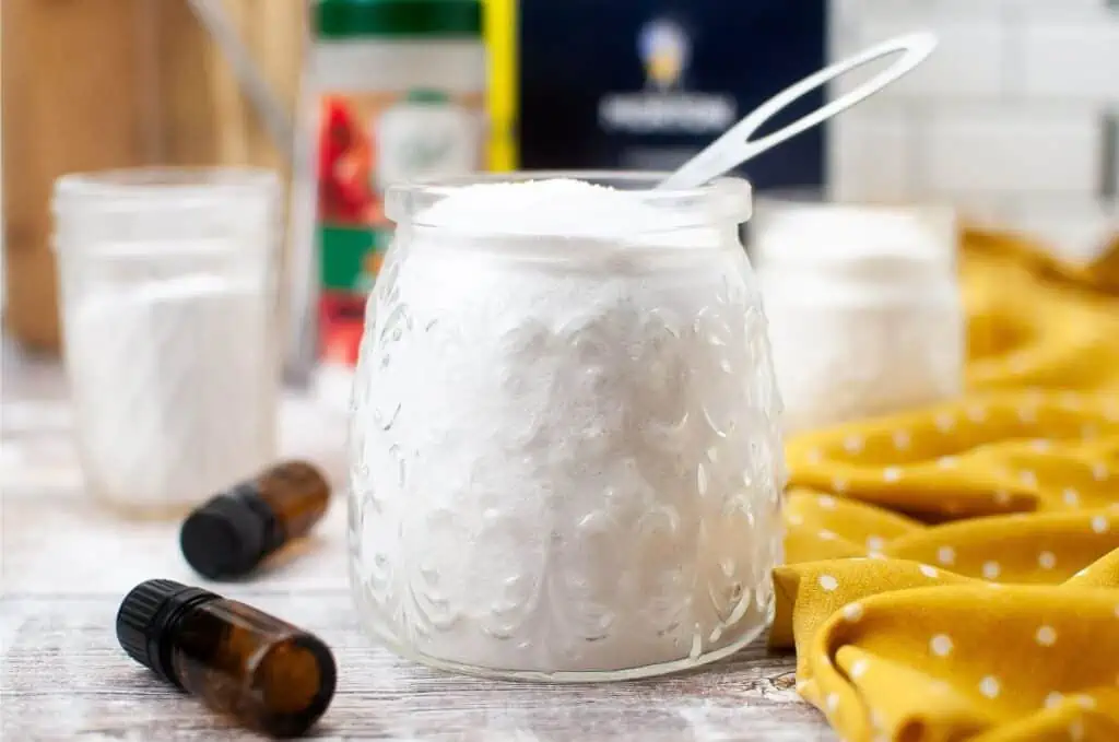 A homemade dishwasher detergent consisting of baking soda and essential oils, stored in a mason jar.