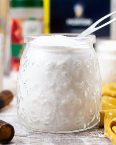 A homemade dishwasher detergent consisting of baking soda and essential oils, stored in a mason jar.