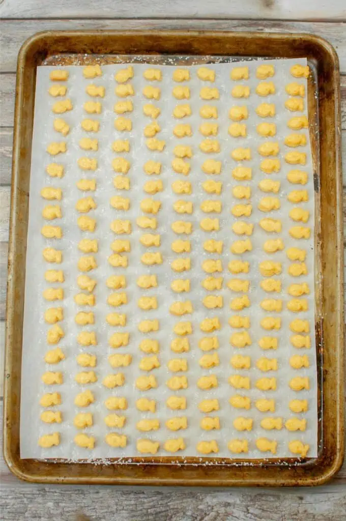 A baking sheet full of cheesy sourdough chips on a wooden table.