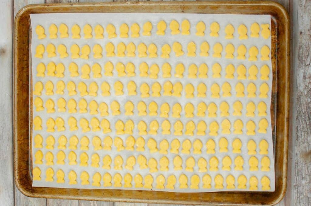 A tray of yellow cookies on a wooden table, ready to be enjoyed.