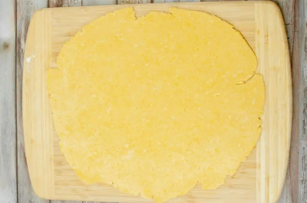 A piece of sourdough dough on a wooden cutting board.