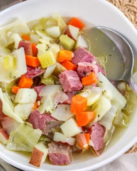 A bowl of corned beef and cabbage soup with a spoon.