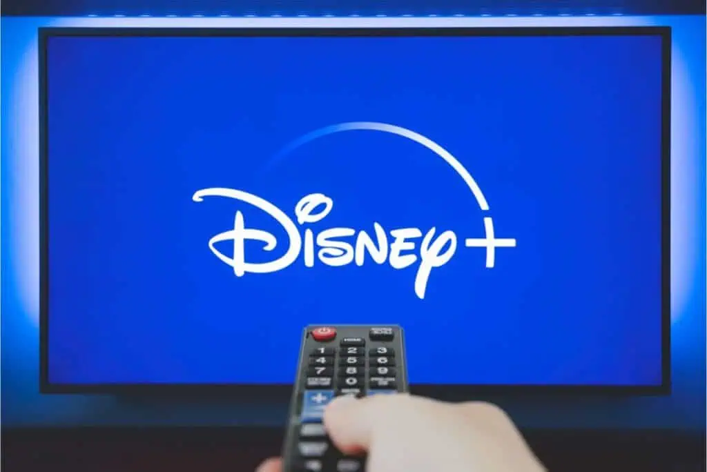 A person holds a remote control towards a TV displaying the Disney+ logo, highlighting the unbelievable $1.99 per month deal.