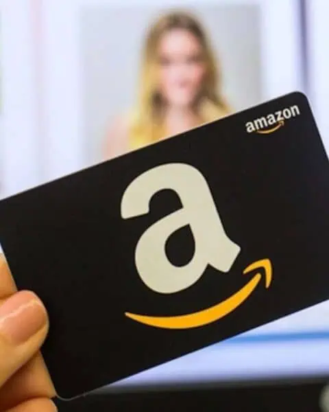 A hand holds an Amazon gift card with the iconic white 