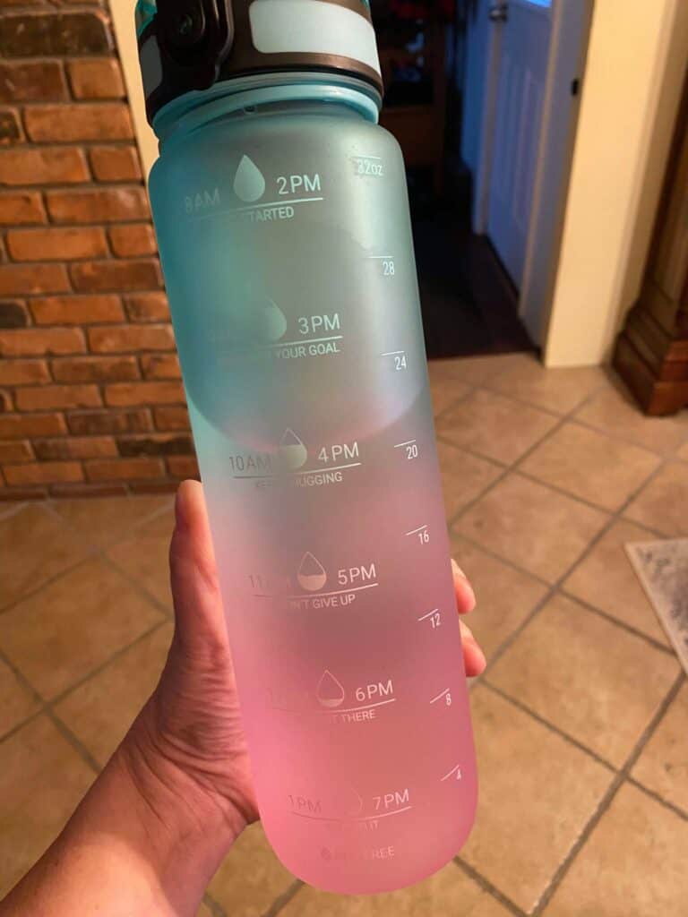 A hand holds a translucent water bottle with time-marked increments from 8 AM to 1 PM and 2 PM to 7 PM, echoing a journey back to healthy habits. The gradient from blue to pink adds a personal touch, much like the passion of blogging from the heart.