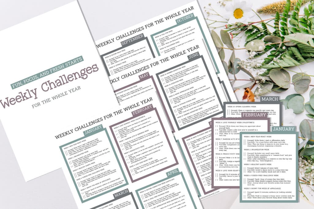A set of printed weekly challenges for the year, titled "Best Year Yet," is displayed on a surface with scattered flowers and leaves, inviting you into a 52-Week Challenge that promises growth and inspiration.