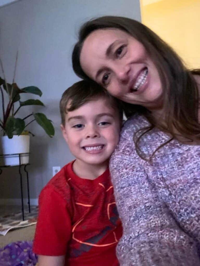 A woman and a child smile for a selfie indoors, capturing the joyful moment next to a potted plant, reminiscent of the warmth found in "The Last Thing He Told Me.