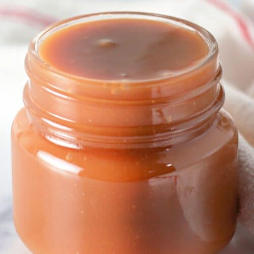A small jar filled with homemade caramel sauce against a soft background, showcasing the results of an easy caramel recipe.