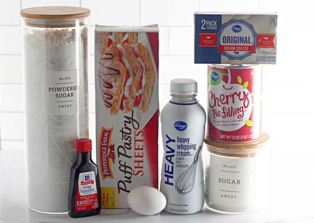 This Cherry Cheesecake Danish recipe features a delightful blend of puff pastry sheets, cream cheese, cherry pie filling, vanilla extract, and heavy whipping cream. Finish with powdered and granulated sugars, plus an egg for a golden touch. Ideal for any dessert lover!.