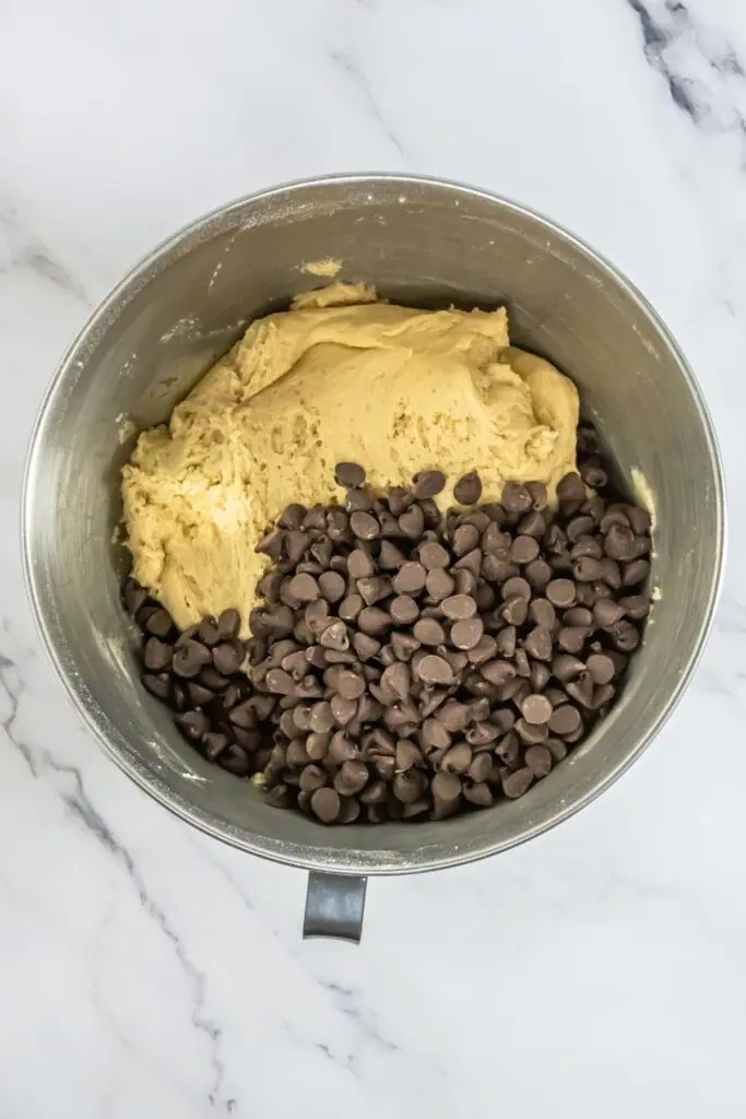 A delightful chocolate chip cookie recipe comes to life as the dough mixes in a bowl on the marble countertop.