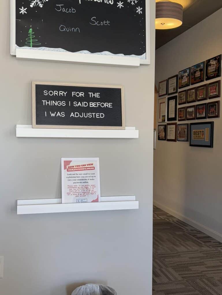 A letter board reads, "SORRY FOR THE THINGS I SAID BEFORE I WAS ADJUSTED." It is mounted on a wall with plaques and awards visible in the background, capturing how my relationship with Mom has changed over the years.