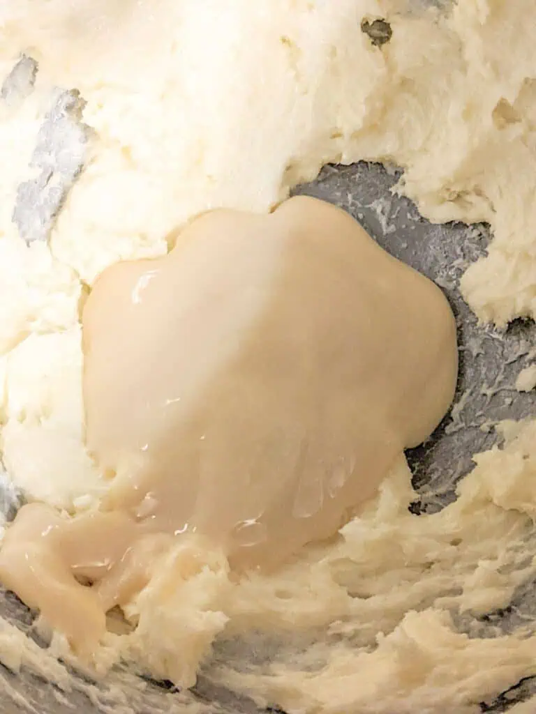 A thick, creamy mixture in a bowl, partially swirled with a lighter layer of condensed milk on top.