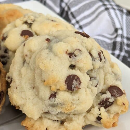 Close-up of cookies with luscious chocolate chips on a white plate, perfectly complemented by a black and white plaid cloth in the background.