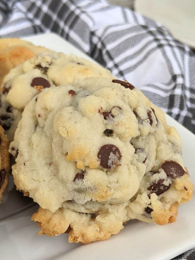 Close-up of cookies with luscious chocolate chips on a white plate, perfectly complemented by a black and white plaid cloth in the background.
