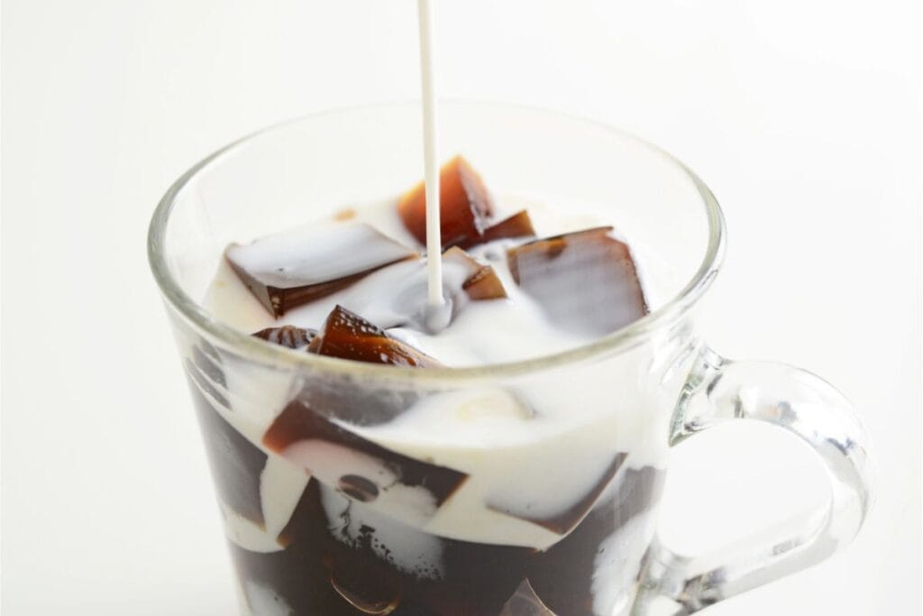 Watch as milk cascades into a clear glass mug filled with shimmering coffee jelly cubes. Curious about this delightful treat? Discover how to make coffee jelly and transform your daily routine into a moment of pure indulgence.