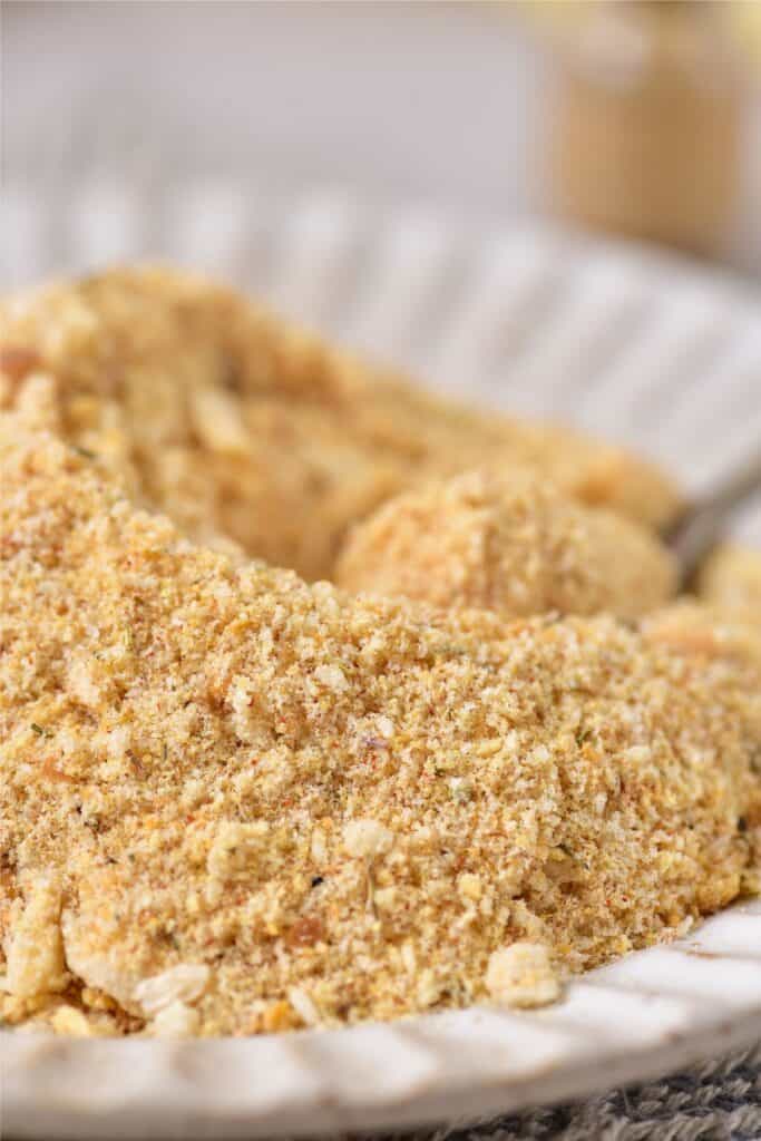 Close-up of a plate with homemade seasoned breadcrumbs, showcasing a textured mix of fine and coarse particles.