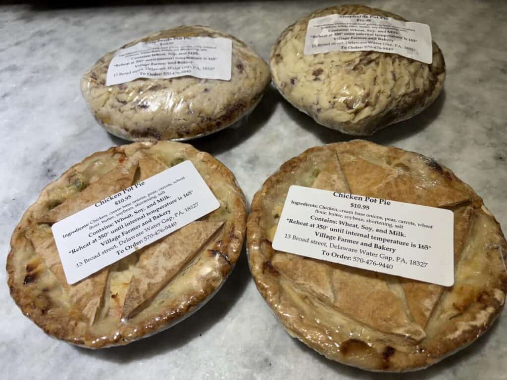 Four neatly packaged chicken pies rest on a marble countertop, each with a personal touch—clearly labeled ingredients and easy baking instructions make it feel like a post from your favorite home chef.