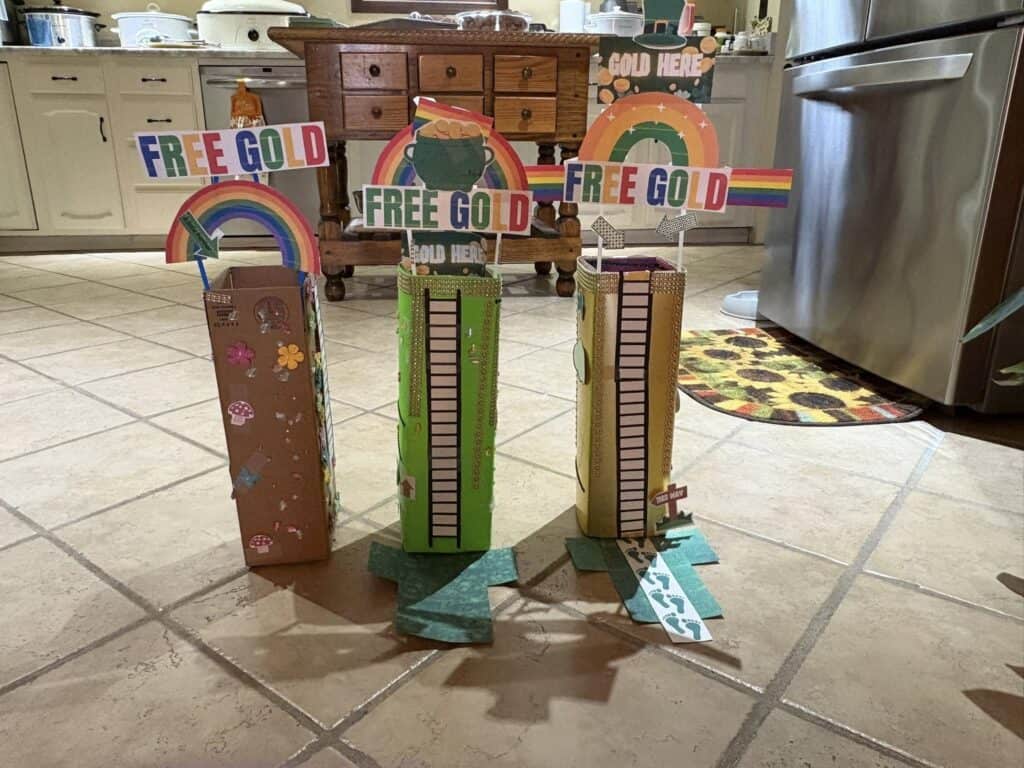 Three tall, colorful cardboard structures with "Free Gold" signs and rainbow designs brighten up the tiled kitchen floor, bringing a playful vibe to the personal post.
