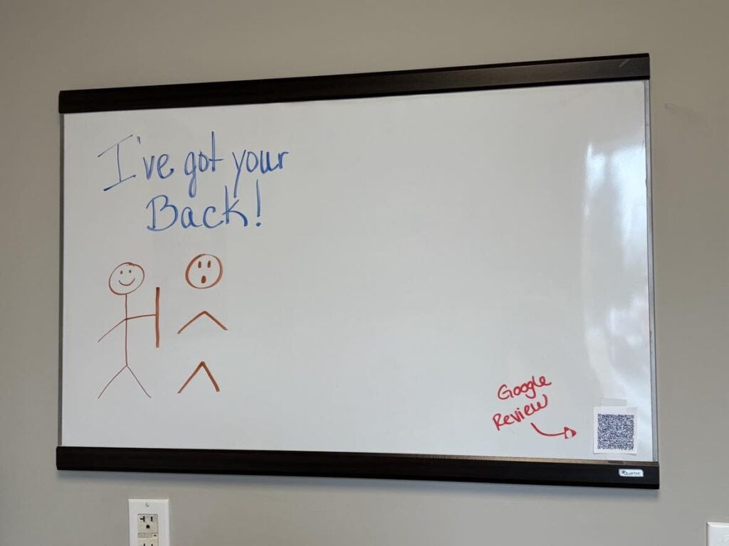 On a personal post, a whiteboard displays a sketch of two stick figures—one holding a stick labeled "I've got your back!" A QR code and "Google Review" feature prominently in the bottom right corner.