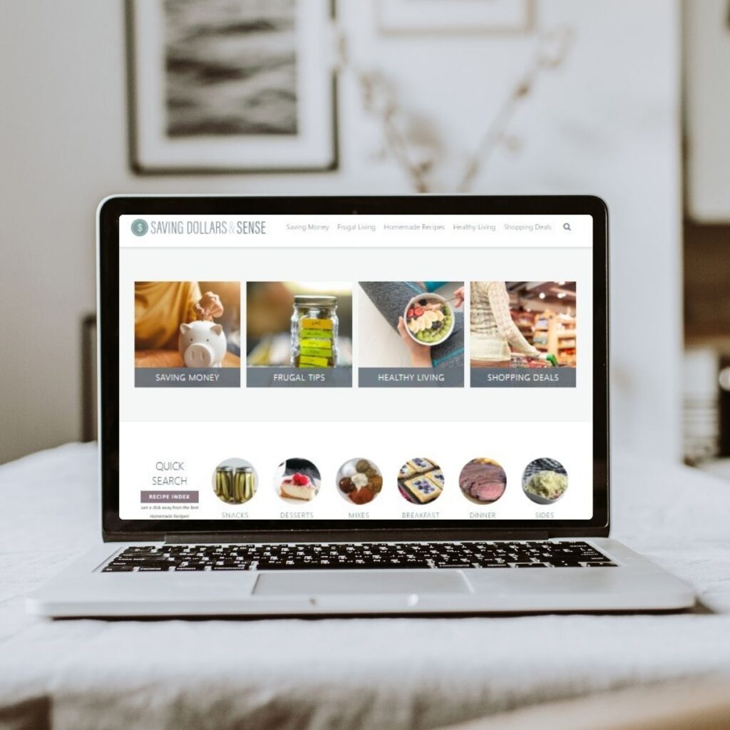 A laptop on a desk displays a website with categories for saving money, frugal tips, healthy living, shopping deals, and choosing peace along your journey.