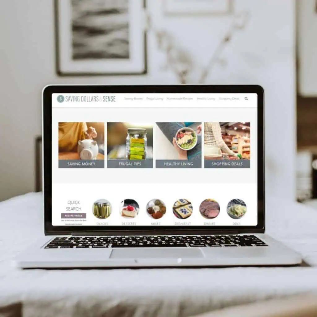 A laptop on a desk displays a website with categories for saving money, frugal tips, healthy living, shopping deals, and choosing peace along your journey.