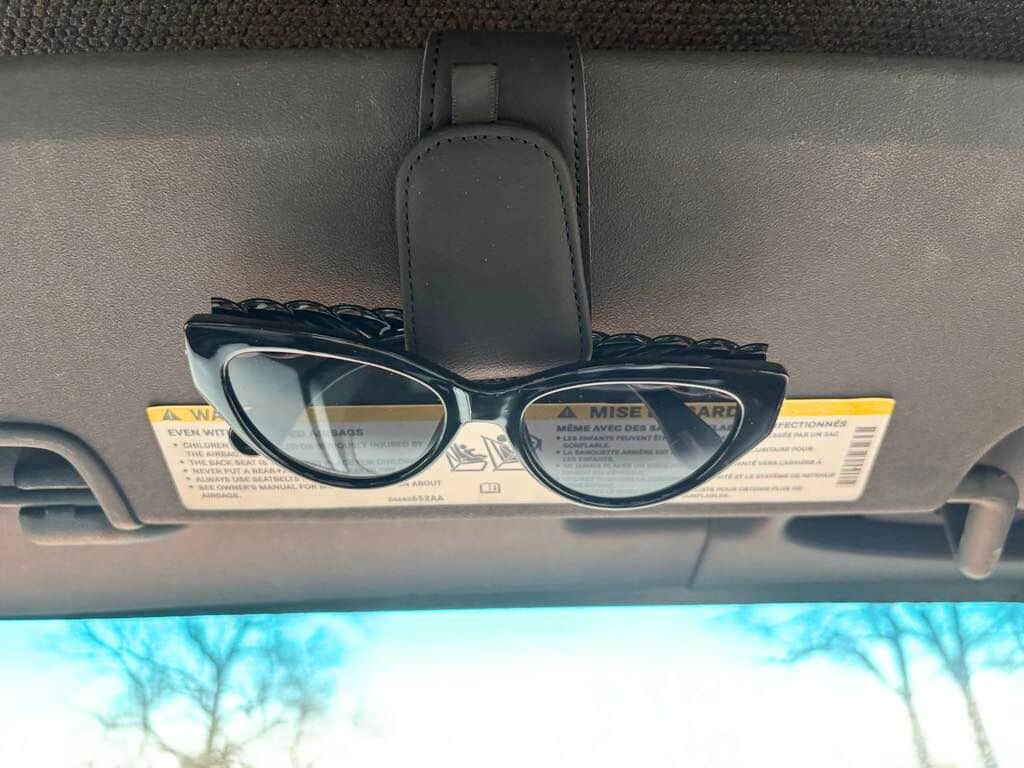 A pair of black sunglasses is clipped to a car's sun visor above the windshield—perhaps ready for another trip out to the family farm, where sustainable agriculture and tradition go hand in hand. Warning labels are visible on the visor.