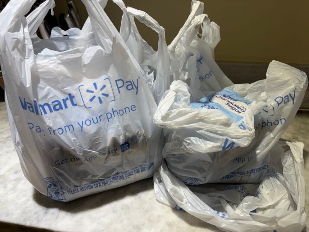 Three Walmart plastic shopping bags filled with groceries—some sweet treats and fresh picks—are placed on a kitchen countertop, ready for a Spring update to your pantry.