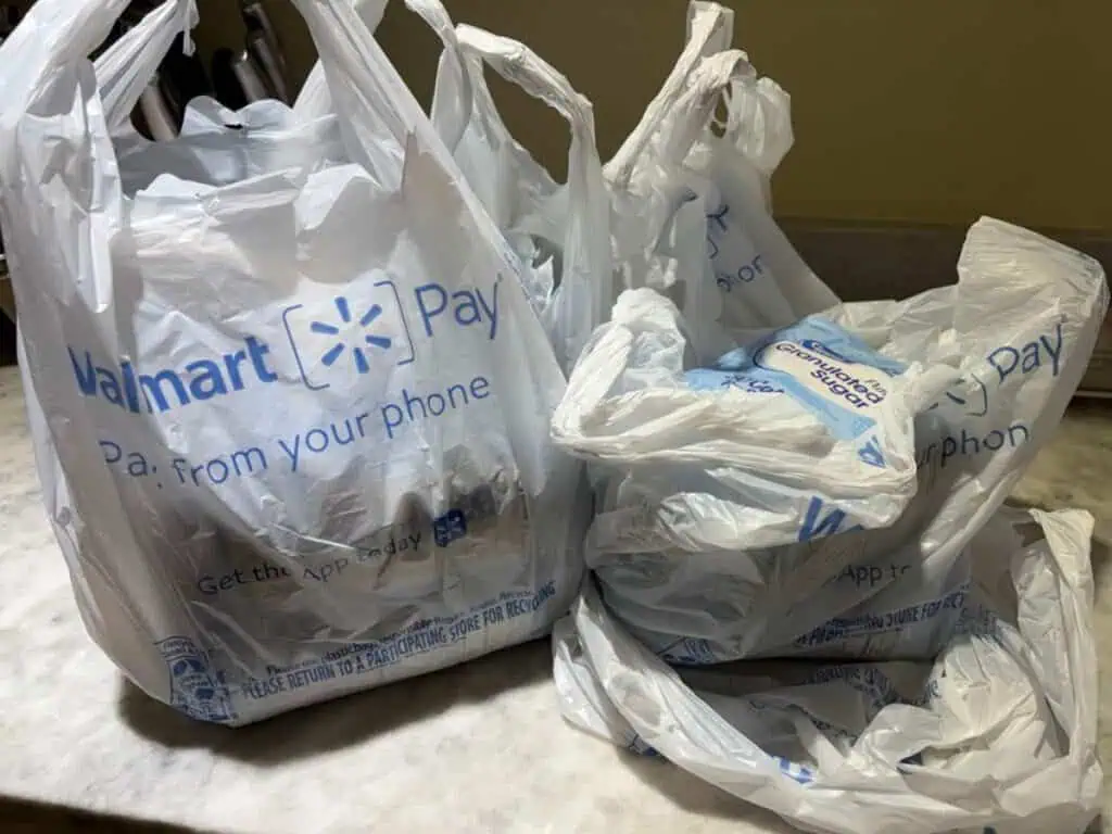 Three Walmart plastic shopping bags filled with groceries—some sweet treats and fresh picks—are placed on a kitchen countertop, ready for a Spring update to your pantry.