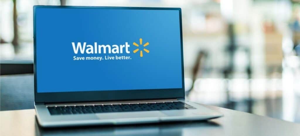 A laptop on a table displays the Walmart logo and slogan "Save money. Live better." on its screen, highlighting the latest Walmart Deals to help you save money at Walmart every day.