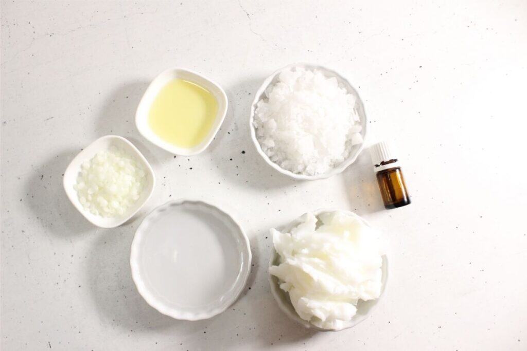 Five small bowls contain various white and clear substances, possibly including Whipped Tallow or Magnesium Lotion, along with a small brown bottle, all arranged on a white surface.