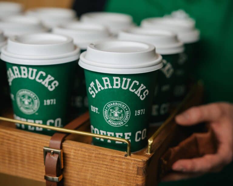 A tray holding several green Starbucks coffee cups with white lids, featuring the Starbucks logo and branding—perfect for enjoying your free Starbucks drink.