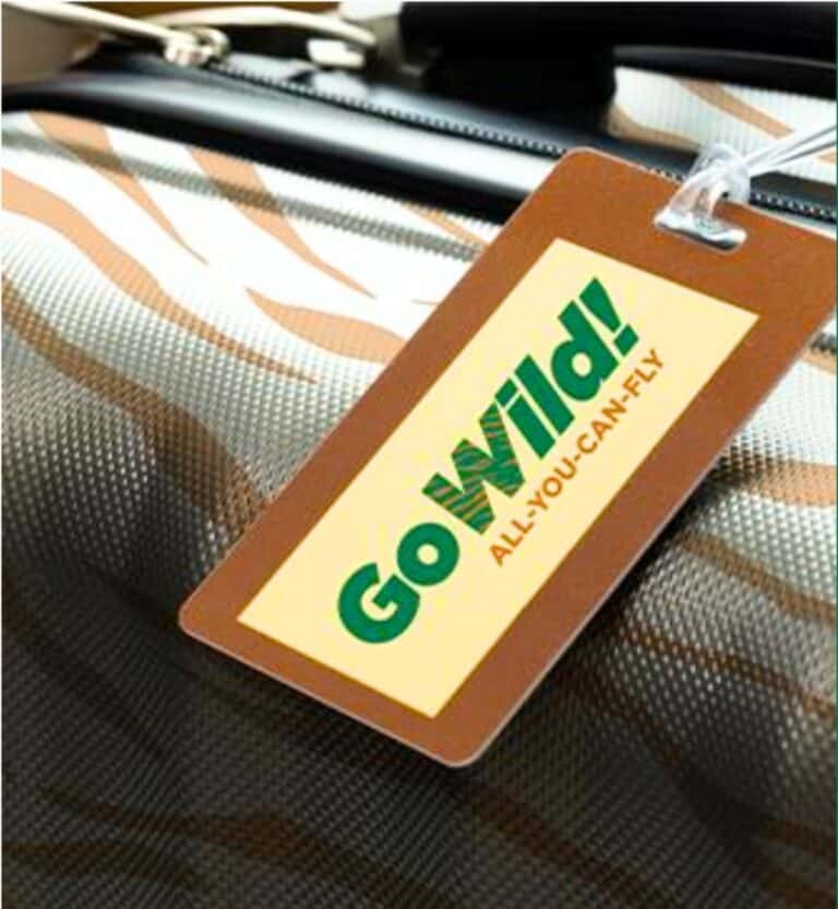 A luggage tag with the words "Go Wild! ALL-YOU-CAN-FLY" attached to a suitcase with a brown and white striped pattern, celebrating Frontier Airlines’ unlimited flights pass for just $299.