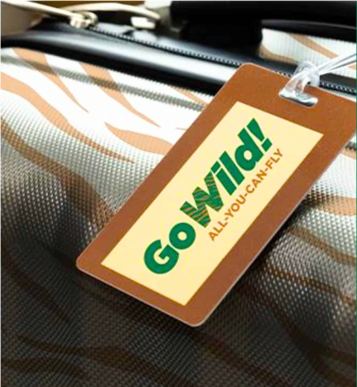 A luggage tag with the words "Go Wild! ALL-YOU-CAN-FLY" attached to a suitcase with a brown and white striped pattern, celebrating Frontier Airlines’ unlimited flights pass for just $299.