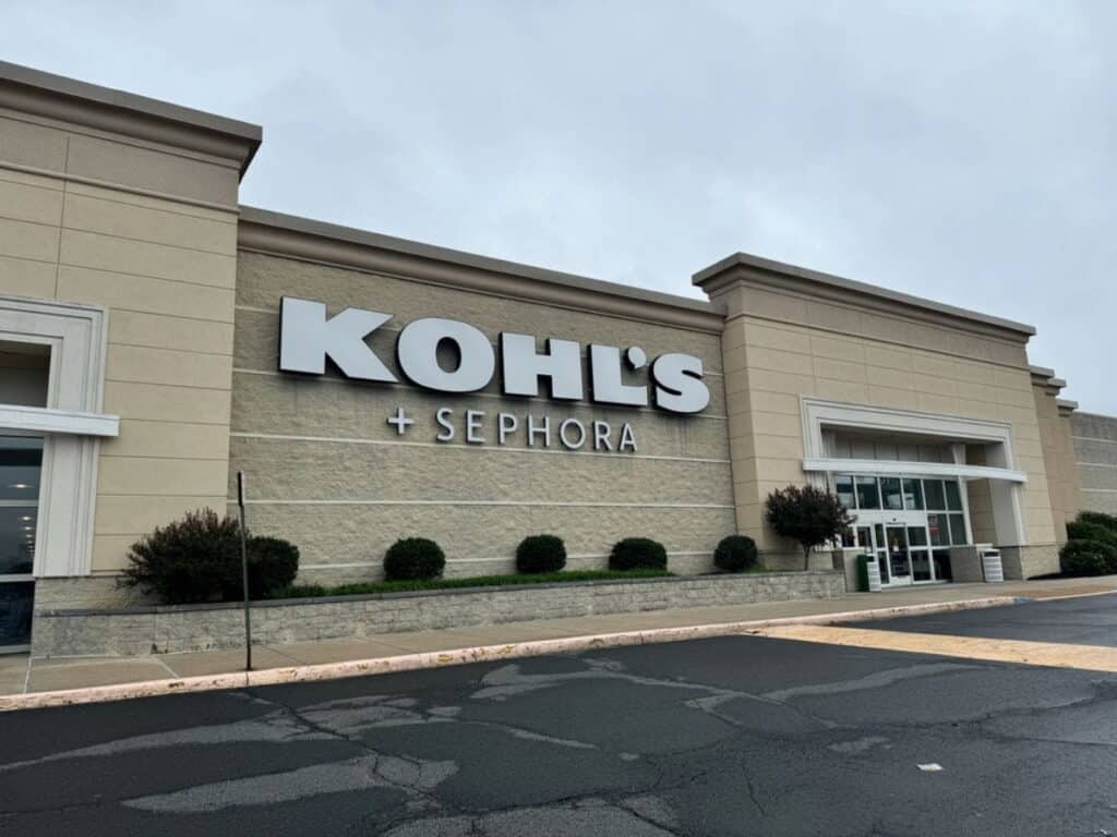 Exterior of a Kohl’s store with Sephora signage, beige facade, glass entrance doors, cloudy sky, and an empty parking lot—perfect for stopping by to enjoy Kohls Rewards benefits on your next visit.