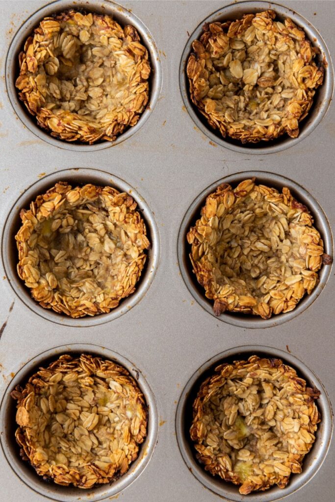 Six Berry Granola Cups with golden edges in a muffin tin, viewed from above.